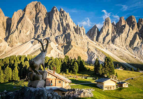 Im Vordergrund die Geisleralm. Dahinter zeigen sich die Dolomiten im Sonnenlicht von ihrer besten Seite.